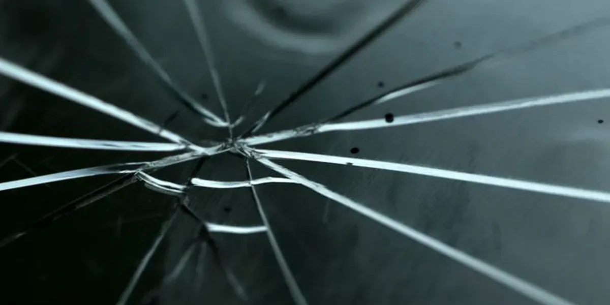 Close-up van een sterretje in een voorruit, met de barsten die eruit vertrekken